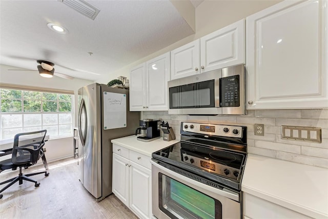 kitchen featuring light countertops, white cabinets, backsplash, and appliances with stainless steel finishes