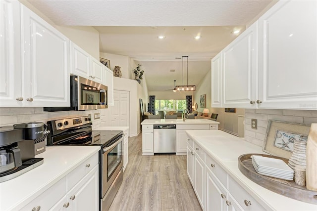 kitchen featuring lofted ceiling, light countertops, white cabinets, appliances with stainless steel finishes, and light wood-type flooring