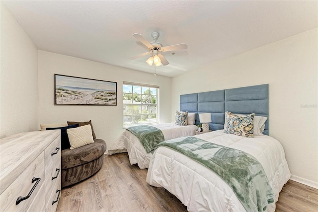 bedroom with ceiling fan, baseboards, and wood finished floors