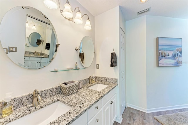 full bath featuring double vanity, wood finished floors, visible vents, and a sink