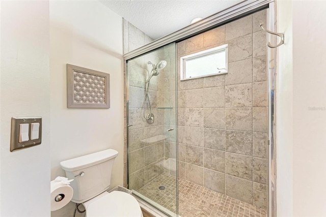 full bath with toilet, a stall shower, and a textured ceiling