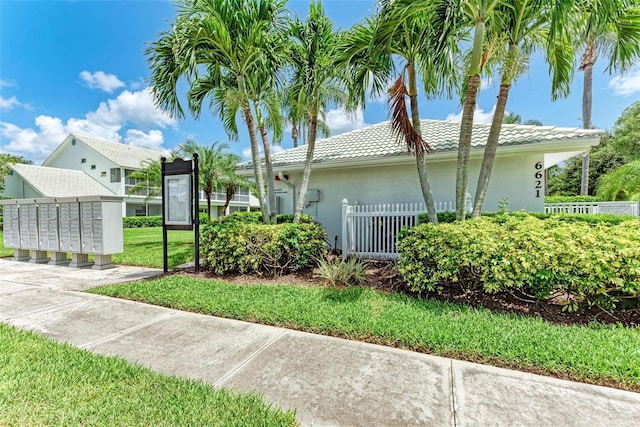 view of side of property with mail area, fence, a tile roof, and stucco siding