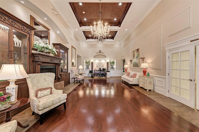 foyer with a chandelier, ornamental molding, a towering ceiling, a decorative wall, and wood-type flooring