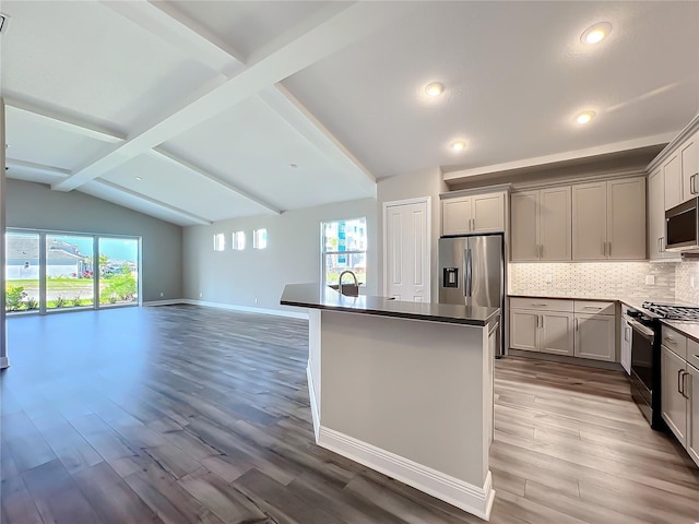 kitchen featuring decorative backsplash, lofted ceiling with beams, plenty of natural light, and stainless steel appliances