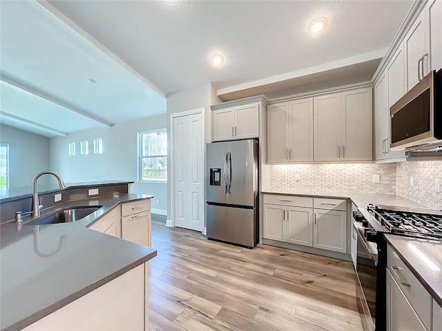 kitchen featuring light wood finished floors, recessed lighting, a sink, stainless steel appliances, and tasteful backsplash