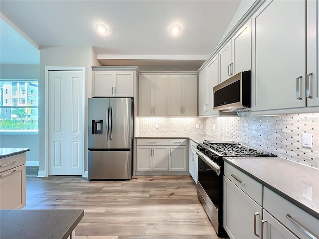 kitchen featuring backsplash, appliances with stainless steel finishes, and light wood-style flooring