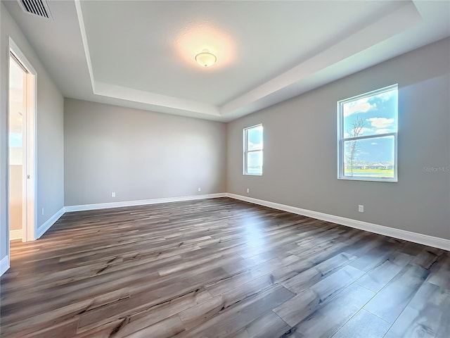 unfurnished room featuring a raised ceiling, baseboards, visible vents, and dark wood-type flooring