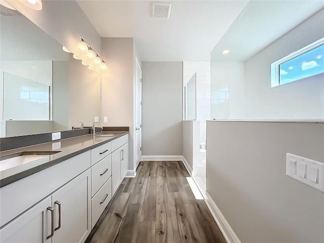 bathroom with walk in shower, wood finished floors, visible vents, and a sink