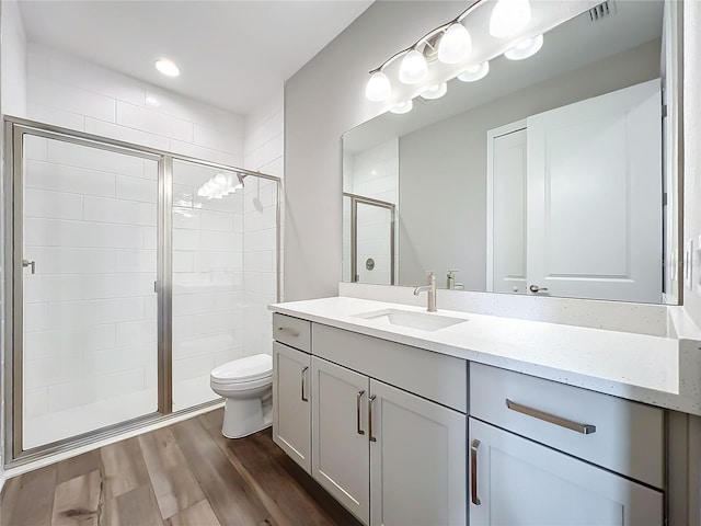 bathroom with vanity, wood finished floors, visible vents, a stall shower, and toilet