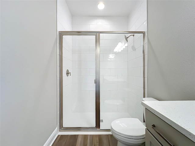 bathroom featuring a stall shower, toilet, wood finished floors, and vanity