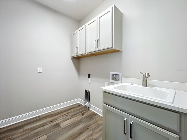 laundry room featuring baseboards, hookup for a washing machine, light wood-style flooring, cabinet space, and a sink