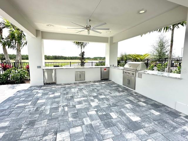 view of patio / terrace featuring grilling area, ceiling fan, fence, and an outdoor kitchen