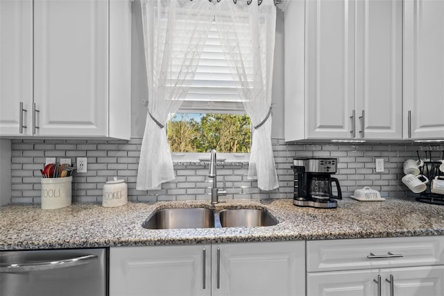 kitchen featuring stainless steel dishwasher, white cabinets, tasteful backsplash, and a sink