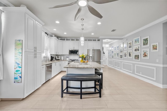 kitchen featuring backsplash, ceiling fan, appliances with stainless steel finishes, a decorative wall, and white cabinetry