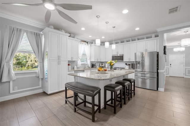 kitchen with decorative backsplash, appliances with stainless steel finishes, white cabinets, and a healthy amount of sunlight