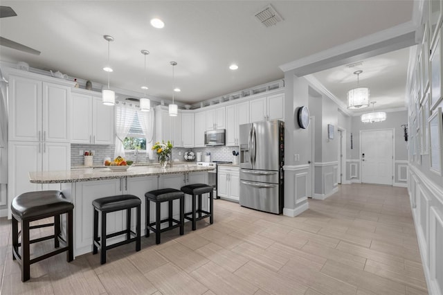 kitchen featuring visible vents, backsplash, a kitchen breakfast bar, white cabinets, and stainless steel appliances