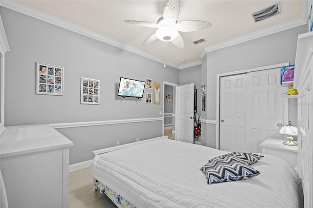 bedroom featuring a closet, visible vents, light wood-style flooring, and ornamental molding