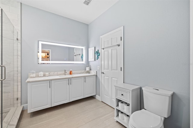 bathroom featuring vanity, wood finished floors, visible vents, a shower stall, and toilet