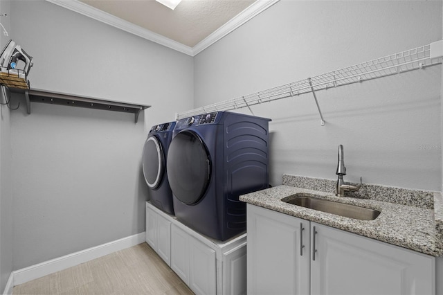 washroom featuring independent washer and dryer, a sink, cabinet space, crown molding, and baseboards