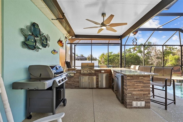 view of patio featuring glass enclosure, exterior kitchen, area for grilling, outdoor wet bar, and ceiling fan