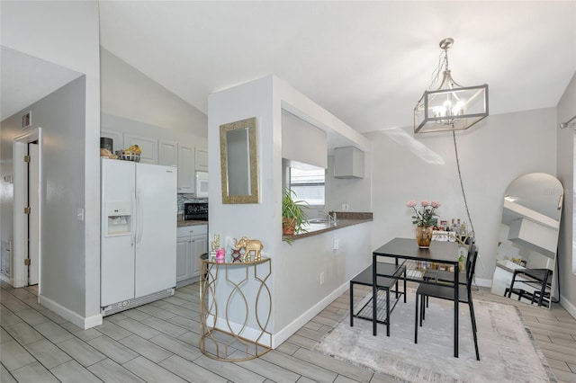 kitchen with wood finish floors, white appliances, arched walkways, lofted ceiling, and a chandelier