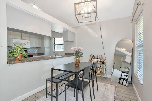 dining space with a notable chandelier, light wood-style flooring, and baseboards