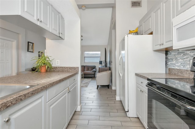 kitchen with visible vents, black electric range, white cabinetry, decorative backsplash, and white microwave