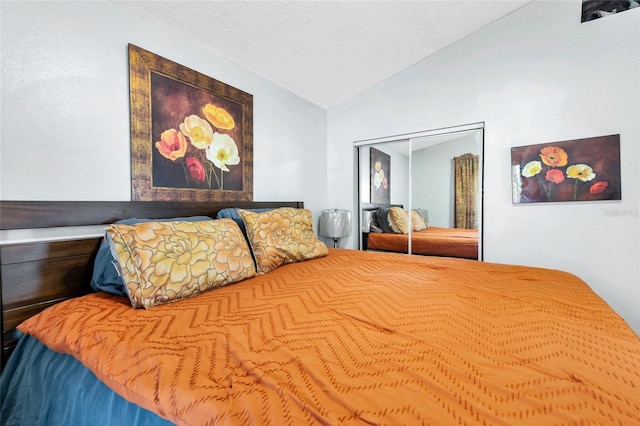 bedroom with a closet, a textured ceiling, and vaulted ceiling