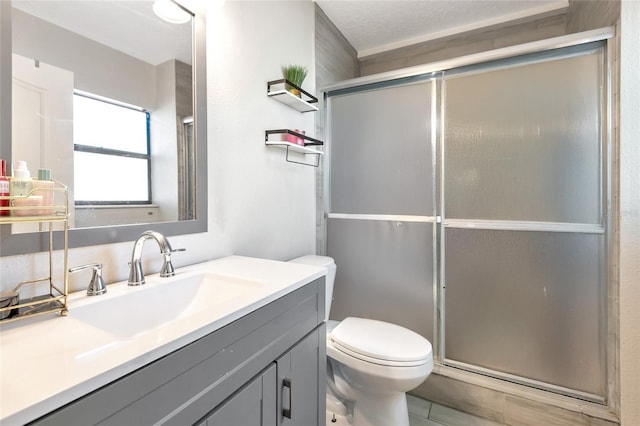 bathroom with a shower stall, toilet, and vanity