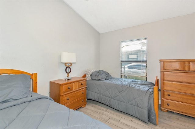 bedroom with wood finish floors and lofted ceiling