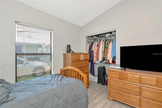 bedroom with wood finish floors, a closet, and lofted ceiling