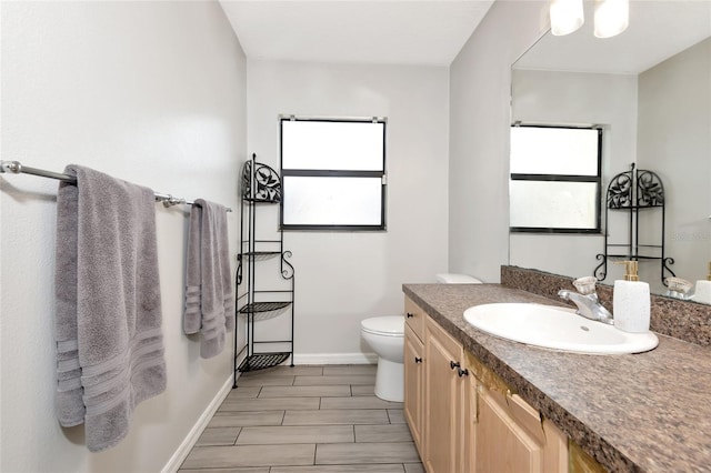 bathroom with baseboards, toilet, and vanity