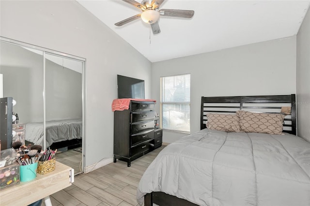 bedroom featuring wood finished floors, a closet, baseboards, ceiling fan, and vaulted ceiling