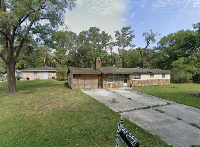 ranch-style home featuring a chimney, stone siding, concrete driveway, and a front lawn