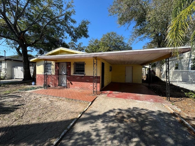 view of front of home featuring a carport, driveway, brick siding, and fence