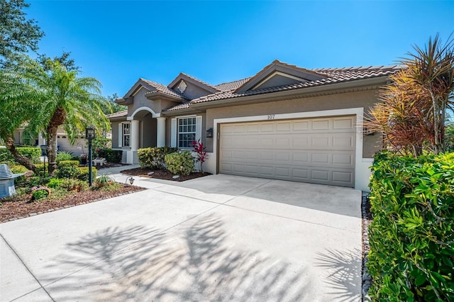 mediterranean / spanish home featuring a tile roof, an attached garage, driveway, and stucco siding