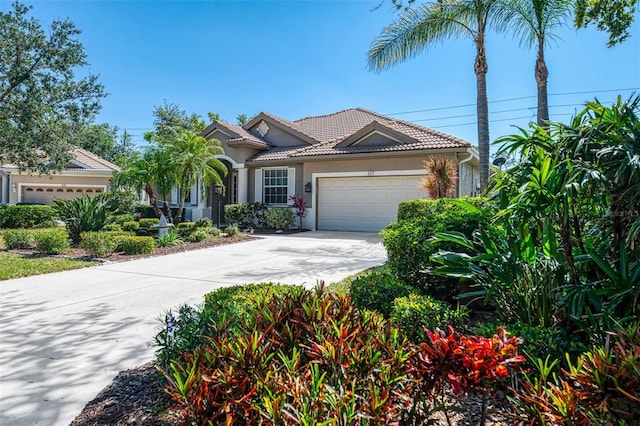 mediterranean / spanish-style house with a garage, stucco siding, driveway, and a tile roof