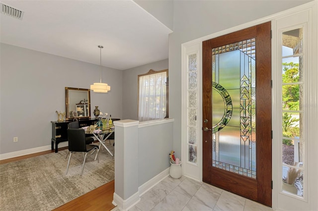 foyer entrance with visible vents, baseboards, and marble finish floor