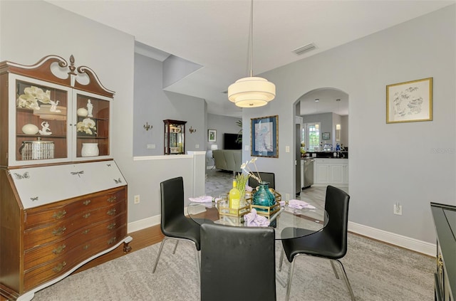 dining space with visible vents, arched walkways, baseboards, and wood finished floors