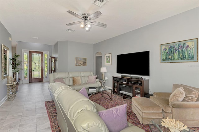 living room featuring arched walkways, visible vents, baseboards, and a ceiling fan