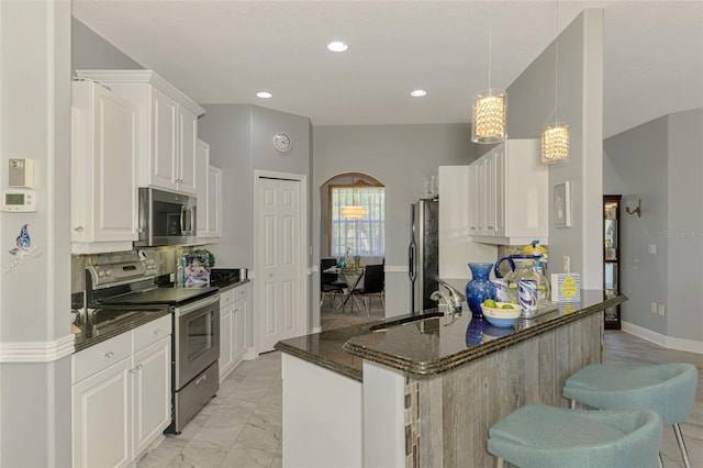 kitchen with a peninsula, a sink, stainless steel appliances, white cabinetry, and marble finish floor