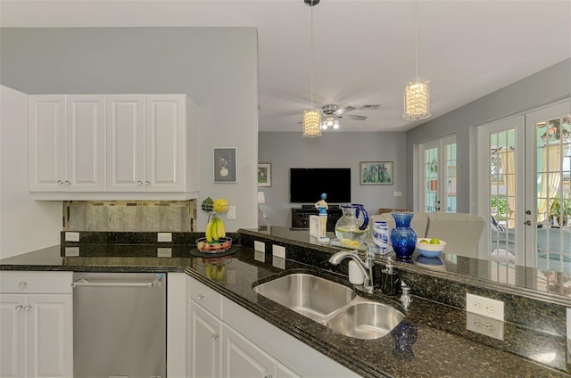 kitchen with open floor plan, dark stone countertops, french doors, white cabinetry, and a sink