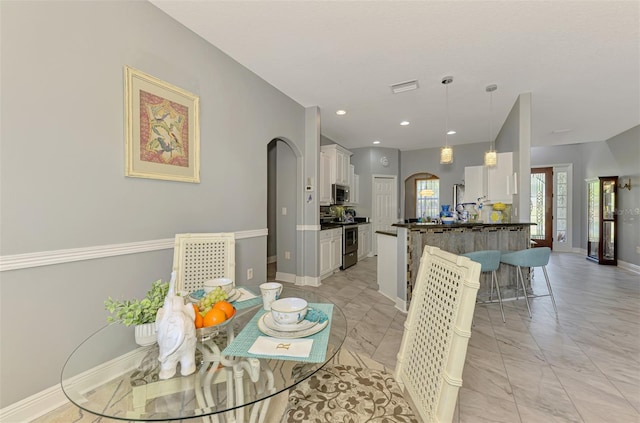 dining room featuring recessed lighting, arched walkways, marble finish floor, and baseboards