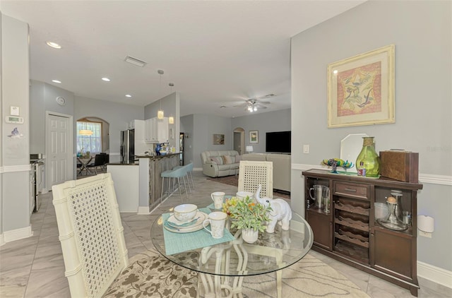 dining space featuring visible vents, arched walkways, marble finish floor, and ceiling fan