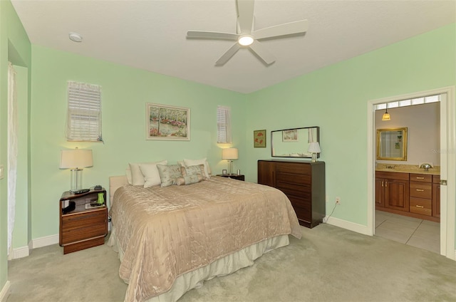 bedroom featuring ensuite bath, a ceiling fan, baseboards, and light carpet