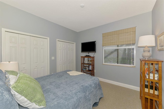 carpeted bedroom with baseboards and two closets