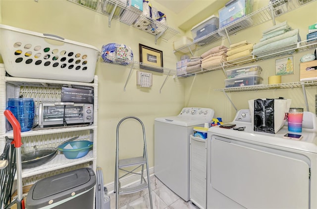 washroom with baseboards, marble finish floor, washing machine and dryer, and laundry area