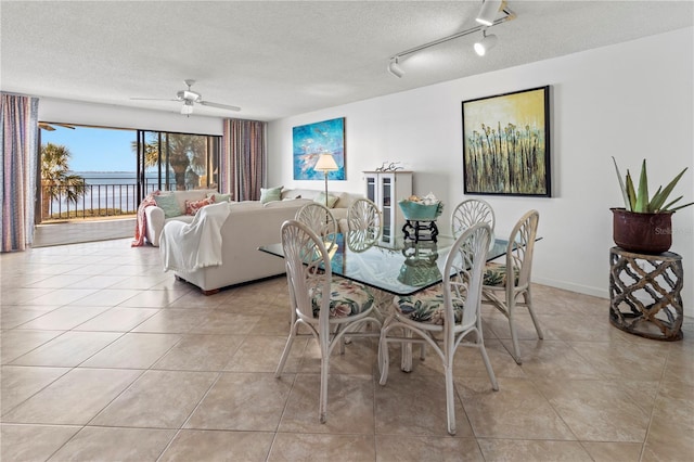 dining space with ceiling fan, a textured ceiling, light tile patterned flooring, and track lighting