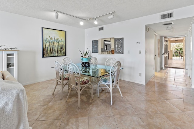 dining area featuring light tile patterned floors, visible vents, and a textured ceiling