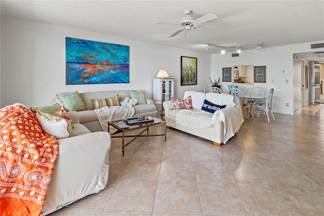 tiled living area with visible vents, a textured ceiling, track lighting, and a ceiling fan